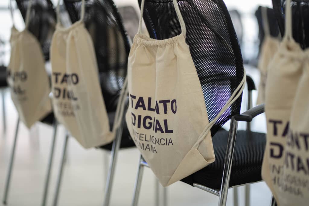 Bolsos de Talento Digital para Chile en sillas de un evento sobre formación digital.